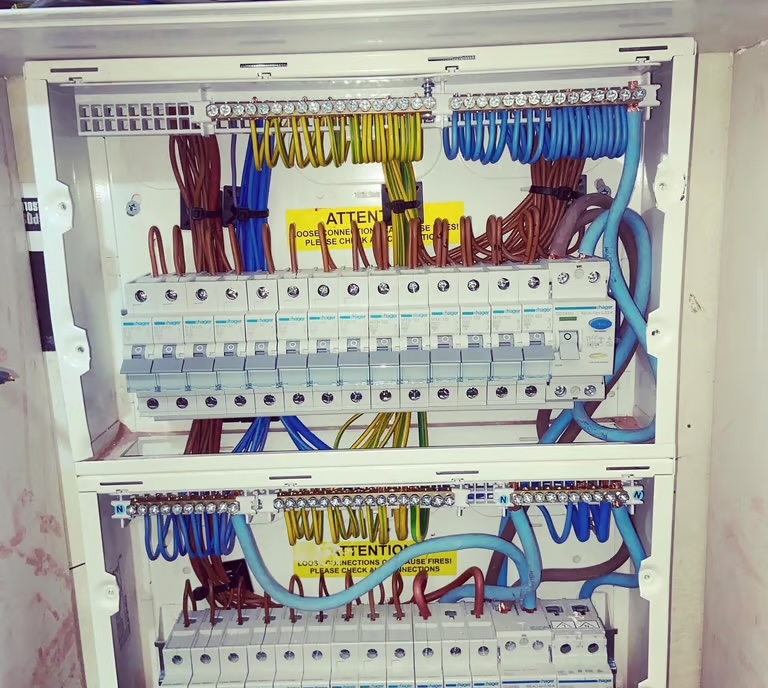 Two consumer units with the covers off, showing the wiring, busbars and circuit ways