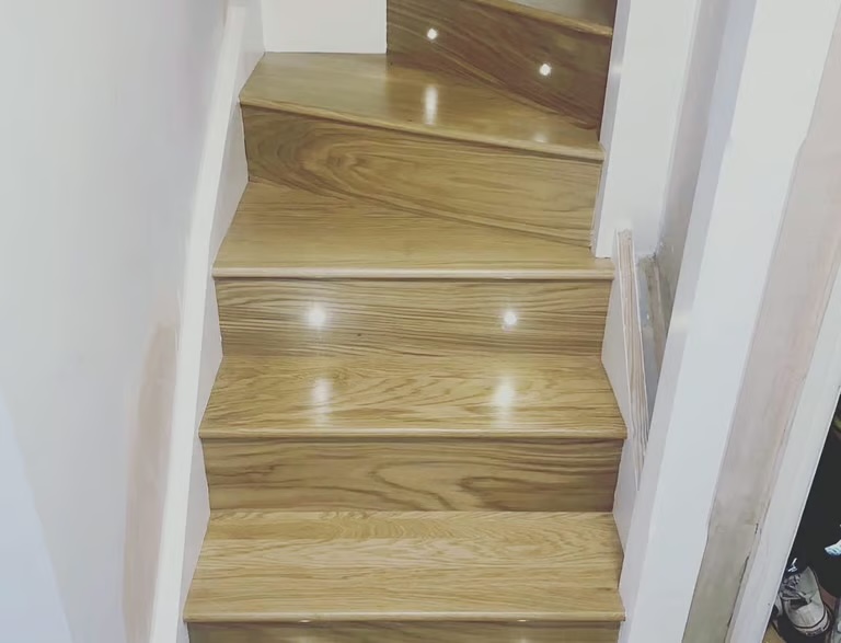 An oak staircase with small LED lights recessed into the treads and risers